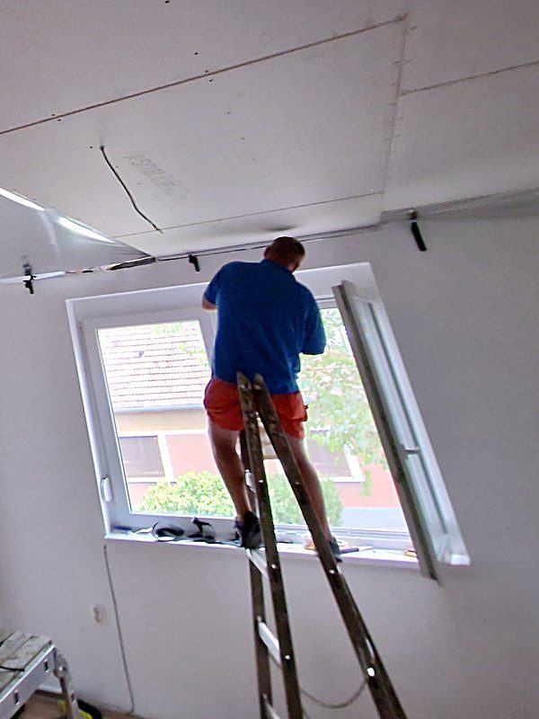Gábor Szilágyi auf der Leiter bei Renovationsarbeiten an einer neuen Decke
